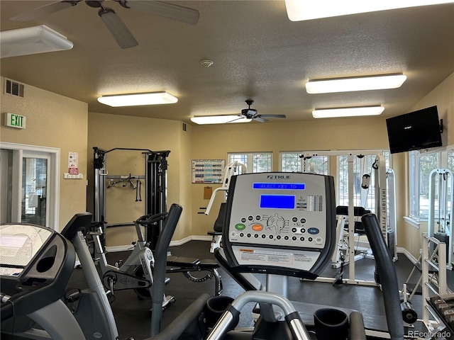 gym featuring a ceiling fan, visible vents, a textured ceiling, and baseboards