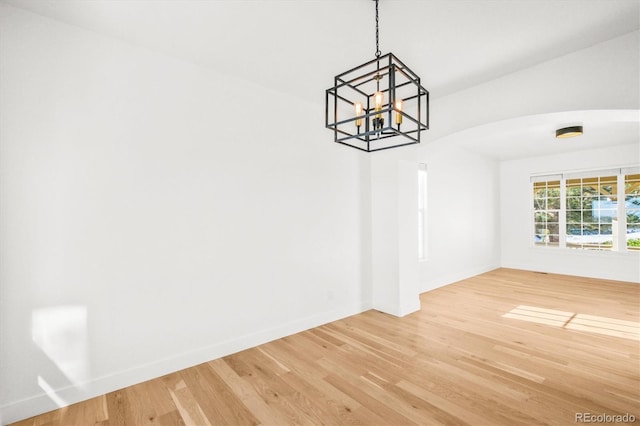 unfurnished dining area with wood-type flooring and an inviting chandelier