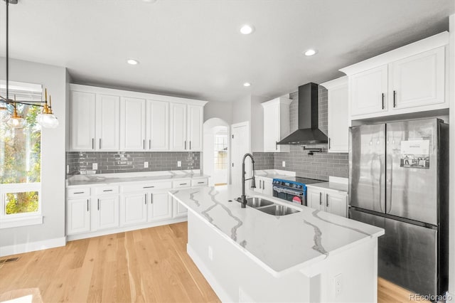 kitchen with white cabinets, wall chimney exhaust hood, pendant lighting, and appliances with stainless steel finishes