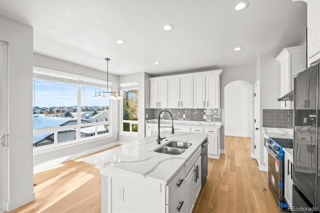 kitchen featuring a healthy amount of sunlight, white cabinets, stainless steel appliances, and an island with sink