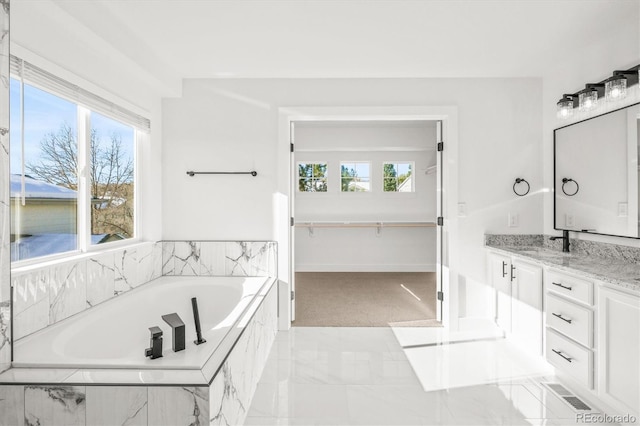 bathroom with vanity and tiled bath