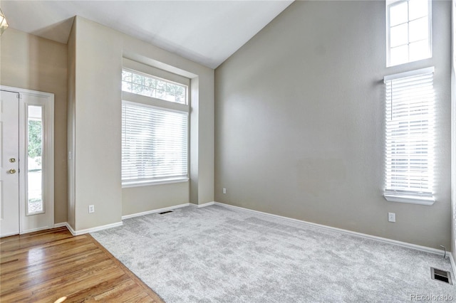 entryway featuring light wood-type flooring, vaulted ceiling, and a wealth of natural light