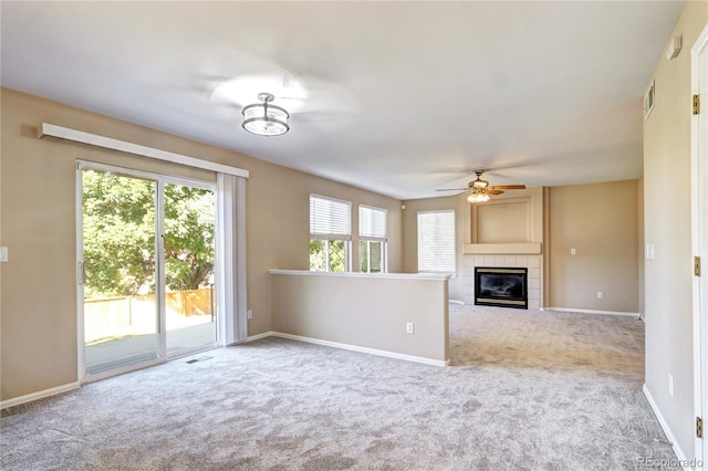 unfurnished living room with ceiling fan, a tile fireplace, and carpet floors