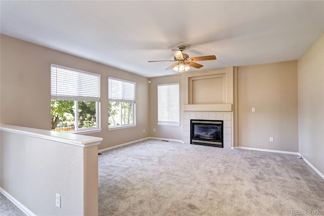 unfurnished living room featuring ceiling fan, light colored carpet, and a fireplace