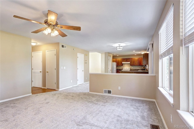 unfurnished living room with ceiling fan and light colored carpet