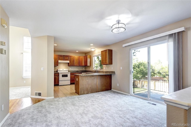 kitchen featuring sink, kitchen peninsula, white range oven, light carpet, and an inviting chandelier