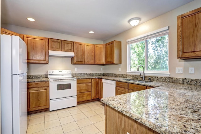 kitchen featuring white appliances, light stone counters, light tile patterned floors, and sink