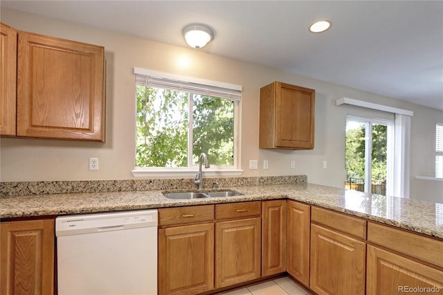 kitchen featuring dishwasher, kitchen peninsula, light stone counters, and sink