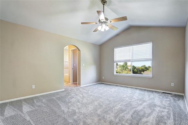 carpeted spare room featuring vaulted ceiling and ceiling fan