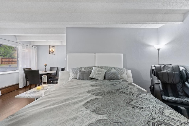 bedroom with wood finished floors, baseboards, and a textured ceiling