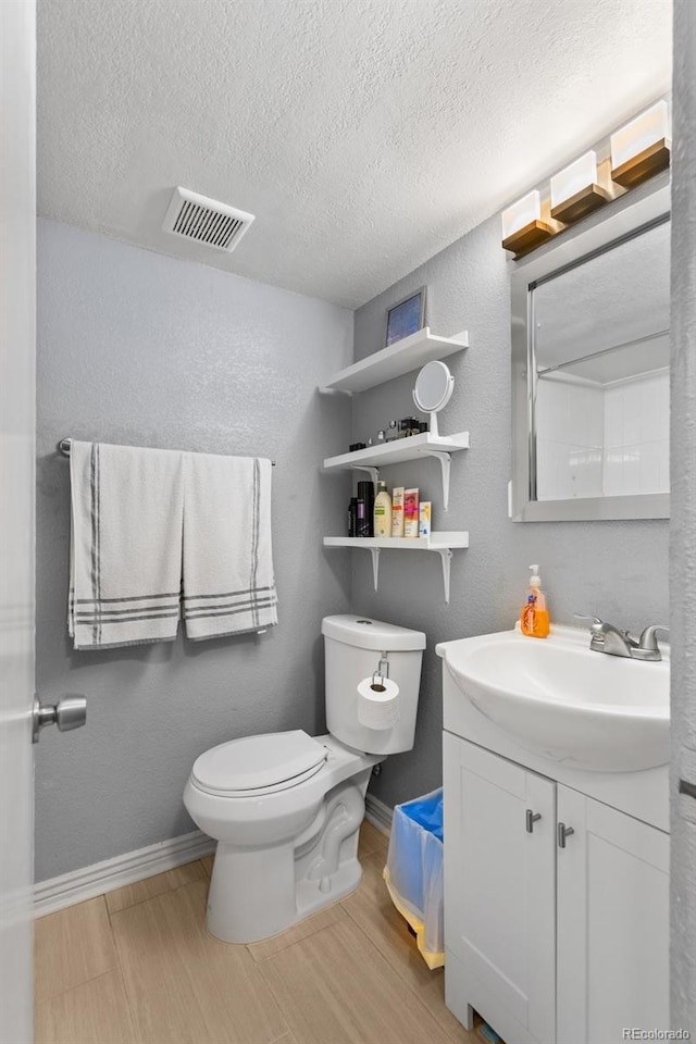 bathroom featuring a textured ceiling, wood finished floors, toilet, baseboards, and vanity