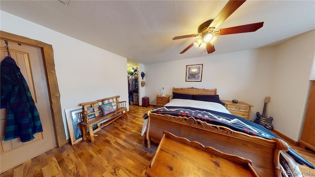 bedroom with a closet, hardwood / wood-style flooring, ceiling fan, a walk in closet, and a textured ceiling