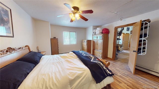 bedroom with a baseboard heating unit, light hardwood / wood-style flooring, and ceiling fan