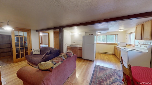 living room with sink, a textured ceiling, a baseboard heating unit, and light wood-type flooring