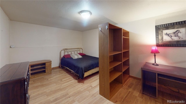 bedroom with light wood-type flooring and a textured ceiling