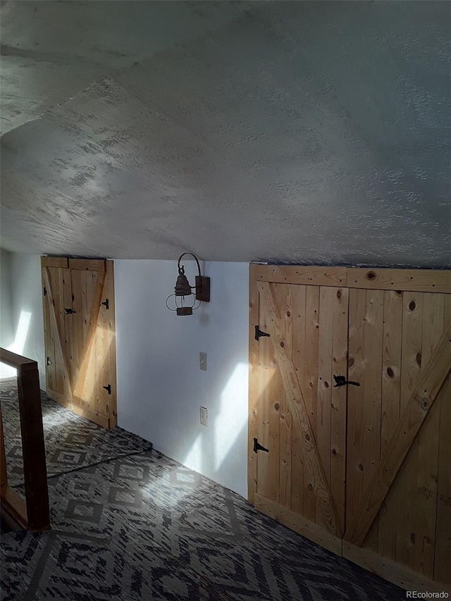 additional living space with wooden walls and a textured ceiling