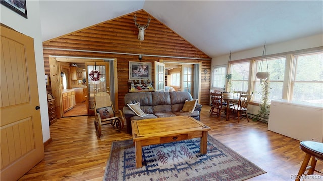 living room with high vaulted ceiling, hardwood / wood-style flooring, and rustic walls