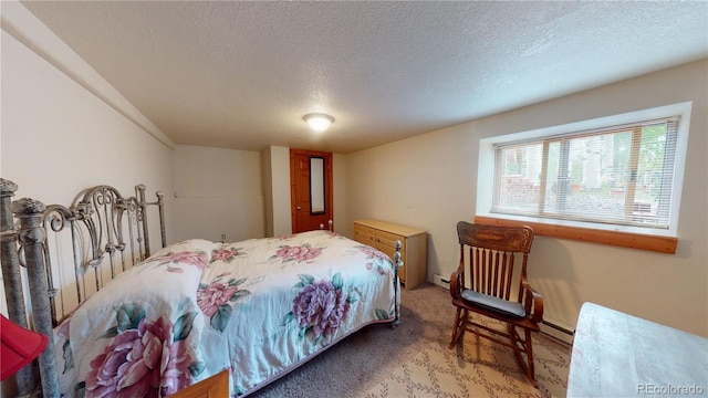 carpeted bedroom with baseboard heating and a textured ceiling