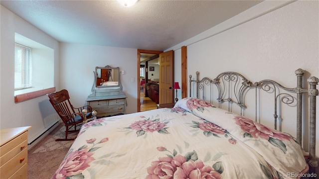 carpeted bedroom with a baseboard heating unit and a textured ceiling