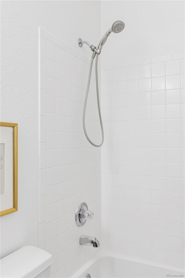 bathroom featuring tiled shower / bath and toilet