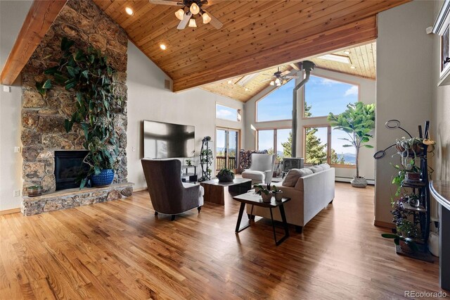30717 Conifer Mountain Dr, Conifer, CO 80433 - living room with a ceiling fan, high vaulted ceiling, wooden ceiling, wood finished floors, and a stone fireplace