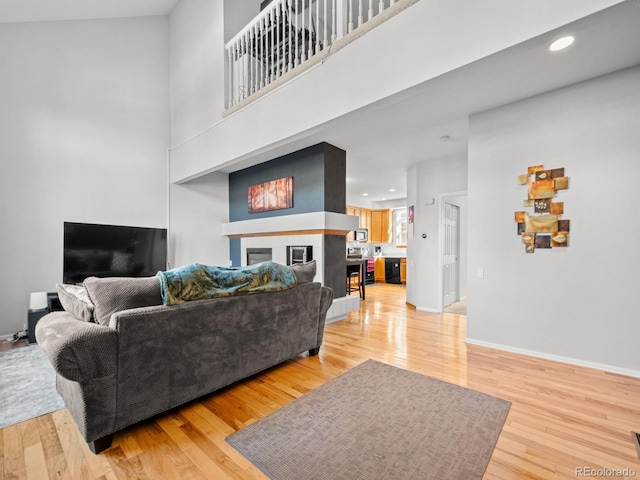 living room featuring a towering ceiling and light wood-type flooring