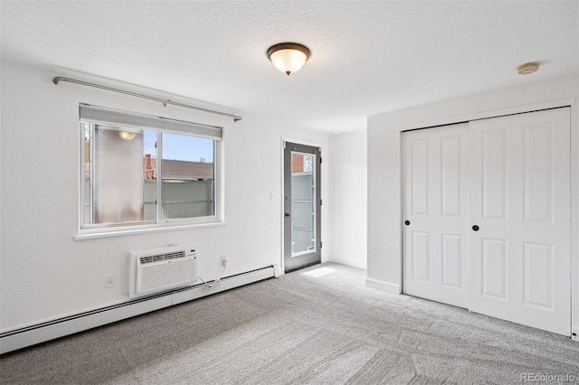 1 N Pearl St Unit 102, Denver, CO 80203 - unfurnished bedroom featuring a baseboard radiator, carpet, a closet, a textured ceiling, and a wall unit AC