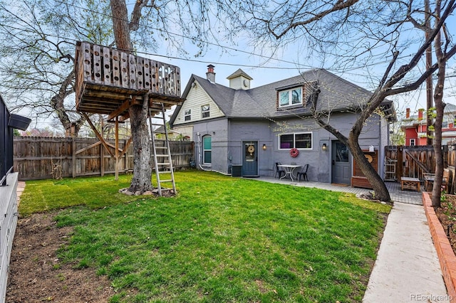 rear view of house with a deck, a shingled roof, a patio area, and a chimney