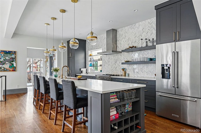 kitchen with high end fridge, wall chimney range hood, open shelves, decorative backsplash, and light countertops