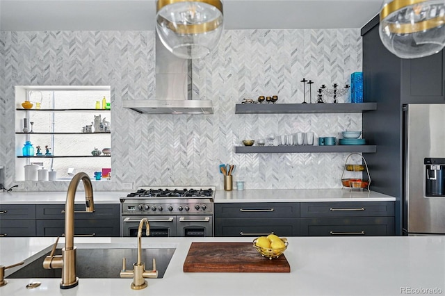 kitchen featuring stainless steel appliances, wall chimney range hood, open shelves, light countertops, and a sink