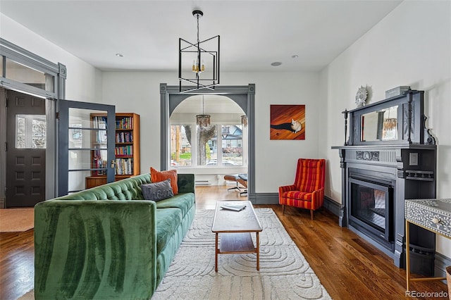 living room with wood finished floors, a chandelier, and a glass covered fireplace