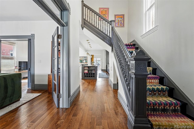 entrance foyer with stairway, wood finished floors, a high ceiling, and baseboards