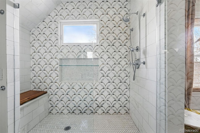 bathroom with a tile shower and vaulted ceiling