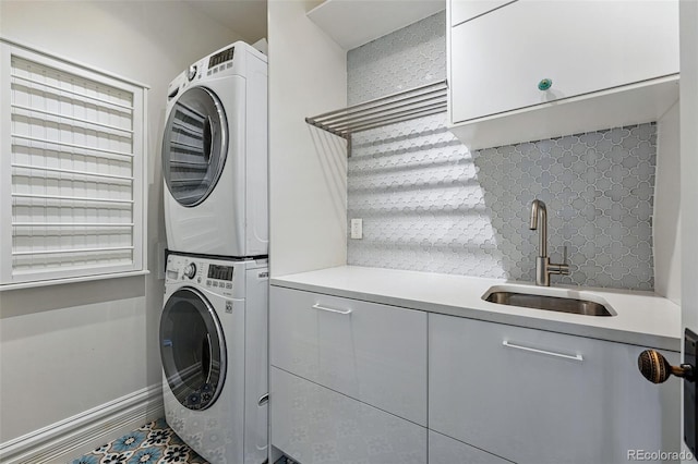 clothes washing area featuring stacked washer and clothes dryer and cabinet space
