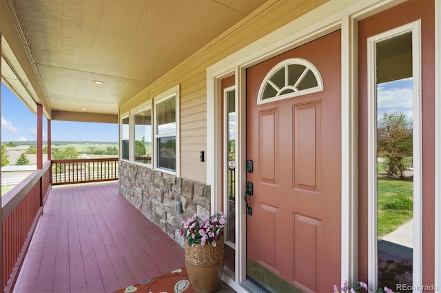 view of exterior entry with stone siding and a porch