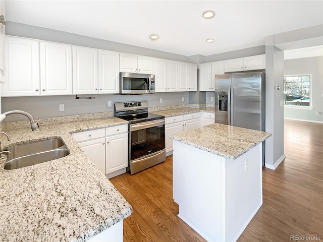 kitchen featuring a kitchen island, white cabinetry, sink, stainless steel appliances, and light stone countertops