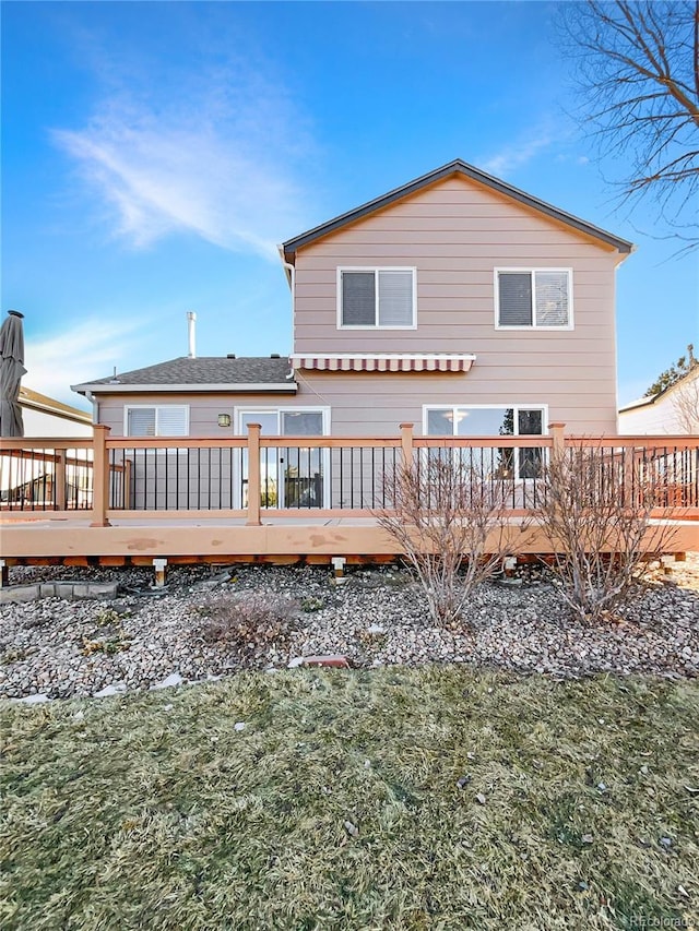 rear view of house featuring a wooden deck and a lawn