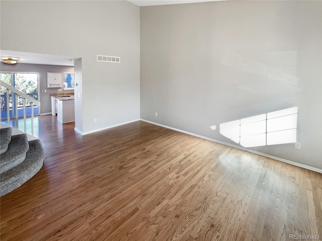 unfurnished living room with hardwood / wood-style flooring and a towering ceiling