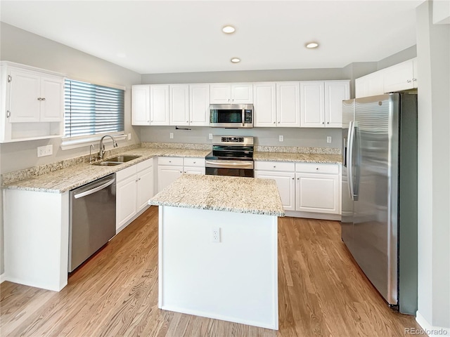 kitchen featuring sink, white cabinets, a center island, light stone counters, and stainless steel appliances