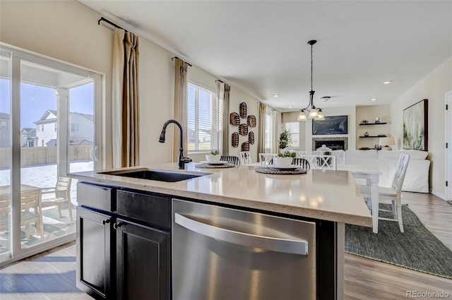 kitchen featuring sink, pendant lighting, dishwasher, light hardwood / wood-style floors, and an island with sink