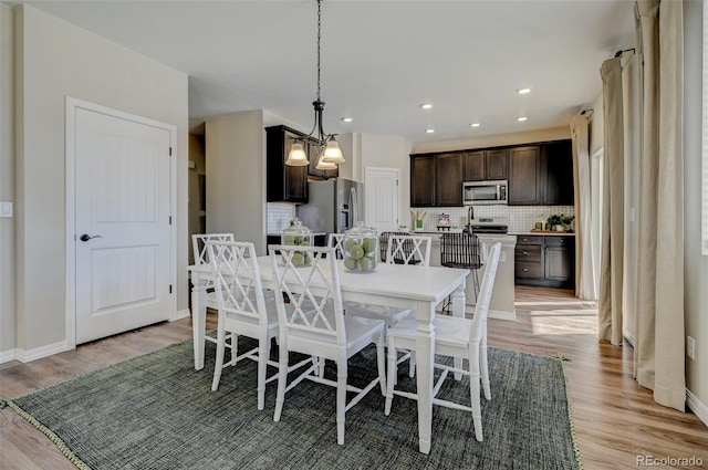 dining space featuring light wood-type flooring and an inviting chandelier