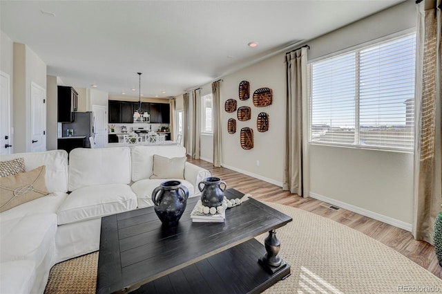 living room with a chandelier, light hardwood / wood-style flooring, and plenty of natural light