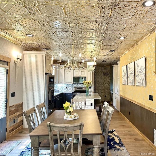 10704 Engelmann Ave, Salida, CO 81201 - dining area with a chandelier, a wainscoted wall, light wood-style flooring, wood walls, and an ornate ceiling