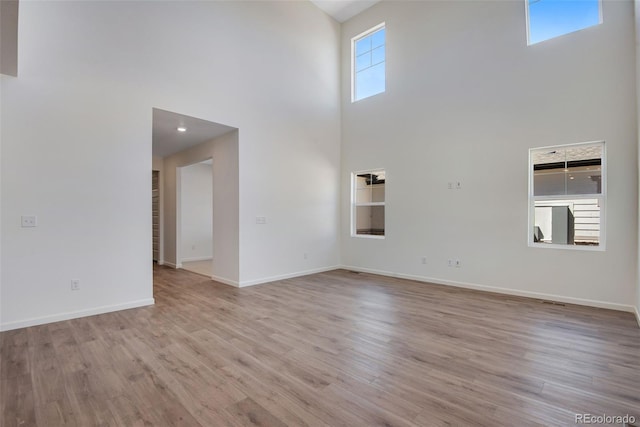 24563 E 34th Ave, Aurora, CO 80019 - unfurnished living room with a high ceiling, light wood-type flooring, and baseboards