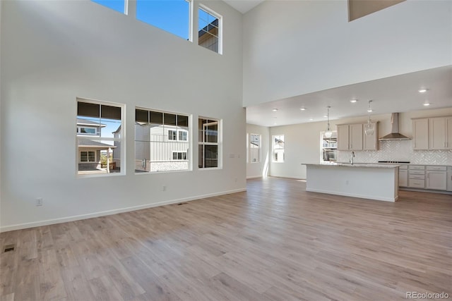 24563 E 34th Ave, Aurora, CO 80019 - unfurnished living room featuring light wood-style floors, recessed lighting, a sink, a high ceiling, and baseboards