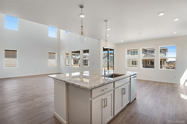 24563 E 34th Ave, Aurora, CO 80019 - kitchen featuring a sink, dishwashing machine, wood finished floors, hanging light fixtures, and a kitchen island with sink