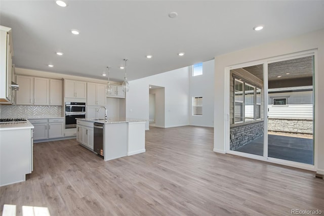 24563 E 34th Ave, Aurora, CO 80019 - kitchen with stainless steel appliances, open floor plan, backsplash, an island with sink, and light wood-type flooring