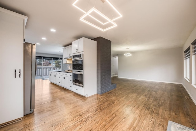 kitchen with white cabinets, light hardwood / wood-style flooring, tasteful backsplash, stainless steel appliances, and a chandelier