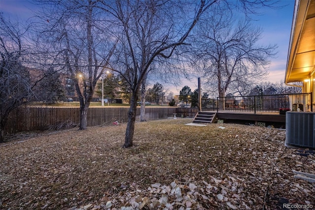 yard at dusk featuring cooling unit and a deck