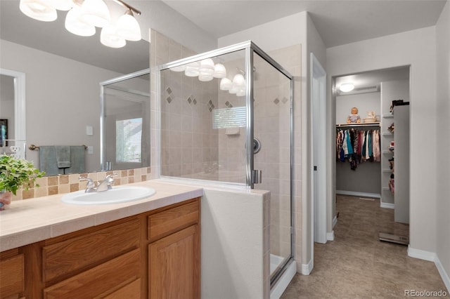 10643 Black Kettle Way, Colorado Springs, CO 80908 - bathroom featuring a walk in closet, vanity, a stall shower, backsplash, and a chandelier